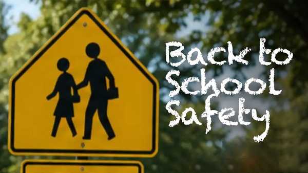 Yellow pedestrian crossing sign in front of trees. Text reads Back to School Safety